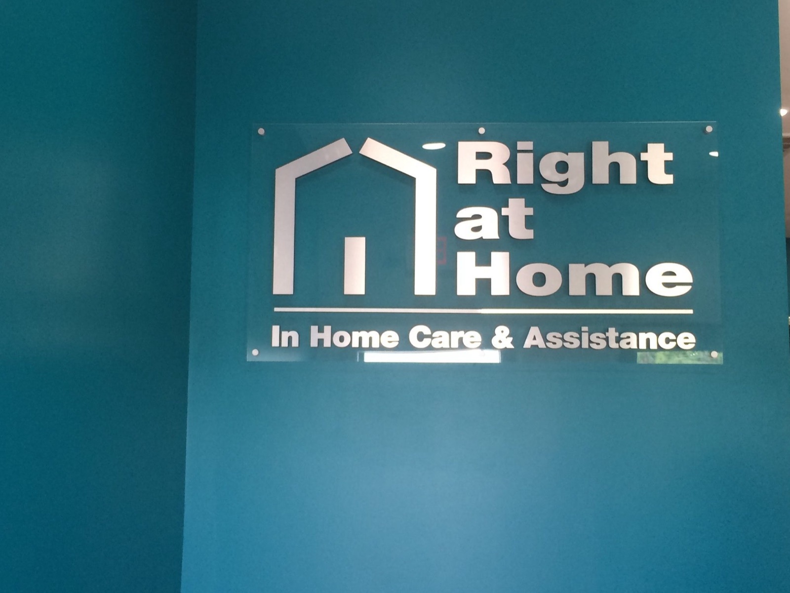 Interior brushed-metal lobby sign reading Right at Home, installed by E&A Signs